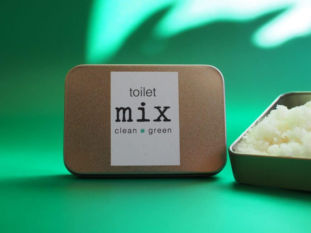 Aluminium Tin On Green Background With Shadows. Open Tin To The Right Showing The Toilet Mix, Pale Yellow Powder.